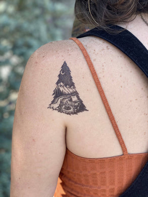 Show off your love of nature with these great temporary tattoos.  A tranquil camping scene within the shape of a pine tree. In this design, there is a sense of stillness on a chilly evening, under a starlit sky and snowcapped mountains. 