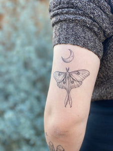 Express yourself with these fun nature-themed temporary tattoos.  Luna moths are a pale green moth, with small eye-shaped patterns on each wing. Their wings each have an elongated double ribbon-like tail, which is one of their most recognizable features. This original hand-drawn design has a furry little body, a wide wingspan, and a crescent moon above.