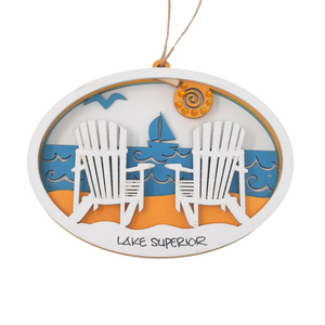 Reminisce about your Northwoods life with this beautiful holiday ornament. Perfect souvenir from your Lake Superior adventures in iconic Apostle Islands, Bayfield, Washburn, and Ashland areas in Wisconsin. Woodcut scene of a sunny beach with two Adirondack chairs and a sailboat. Size: 5" x 3.5"