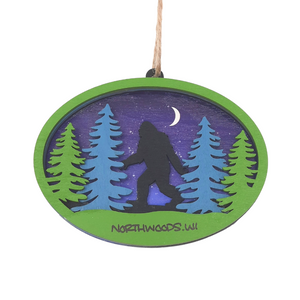 Reminisce about your Northwoods life with this beautiful holiday ornament. Perfect souvenir from your Northwoods, Wisconsin adventures in iconic Apostle Islands, Bayfield, Washburn, and Ashland areas. Woodcut scene of a Sasquatch among the trees & under the northern lights. Size: 5" x 3.5"