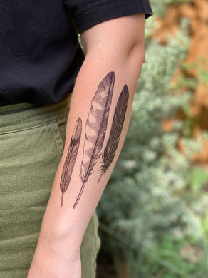 Express yourself with these fun nature-themed temporary tattoos.  Feathers represented are a small mockingbird feather, a long hawk feather, and a black mystery feather, perhaps a raven, crow, or grackle. Measures 6.25